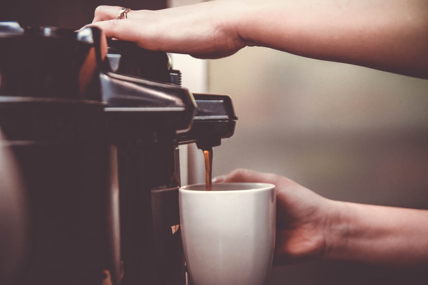 Person Pouring Coffee from a Coffee Machine